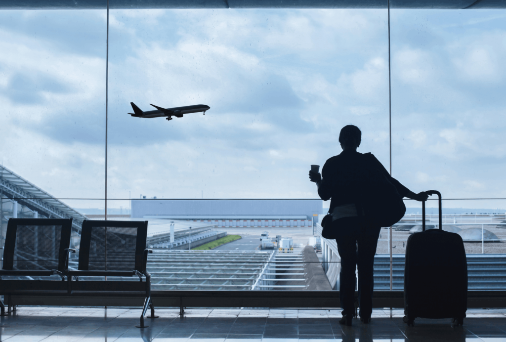 Reisender wartet mit Koffer am Flughafen auf seinen Flug